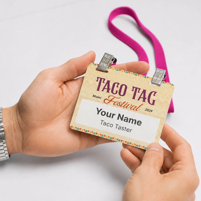 A person holds a taco tag miami festival small adhesive name badge attached to a pink double clip lanyard