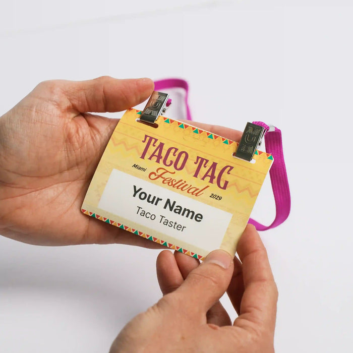 Hands holding a 4 x 3 IntelliBadge event name badge with a magenta double-clip lanyard